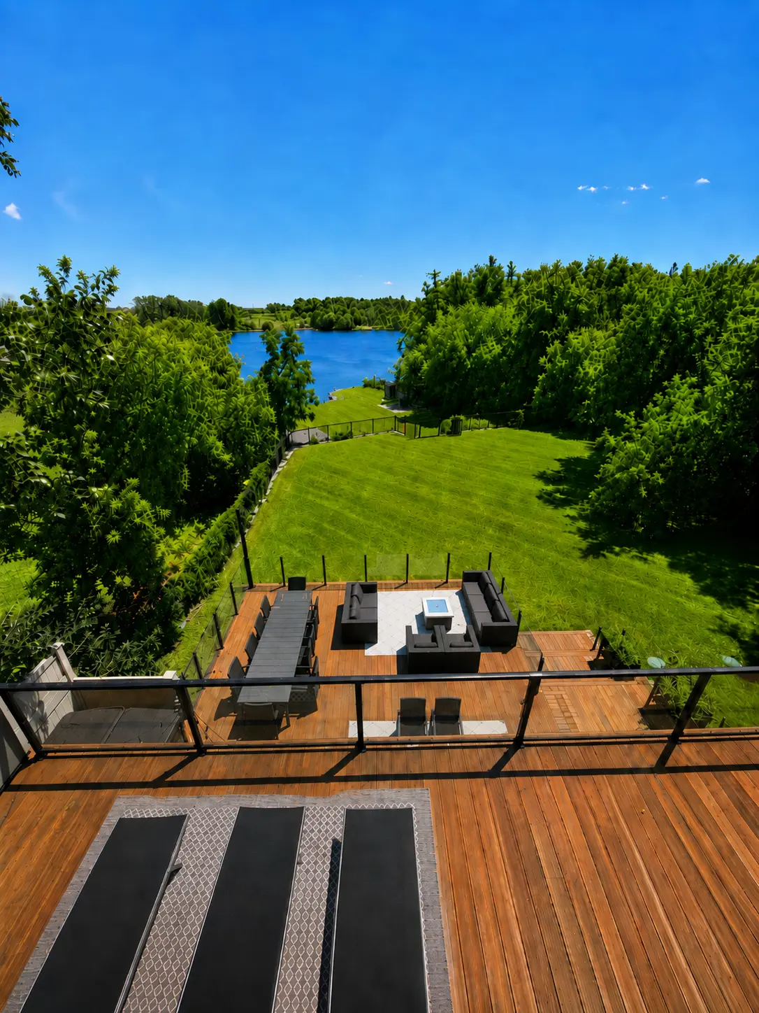 Cedar deck with fire table and lounge seating above a lawn running to the river